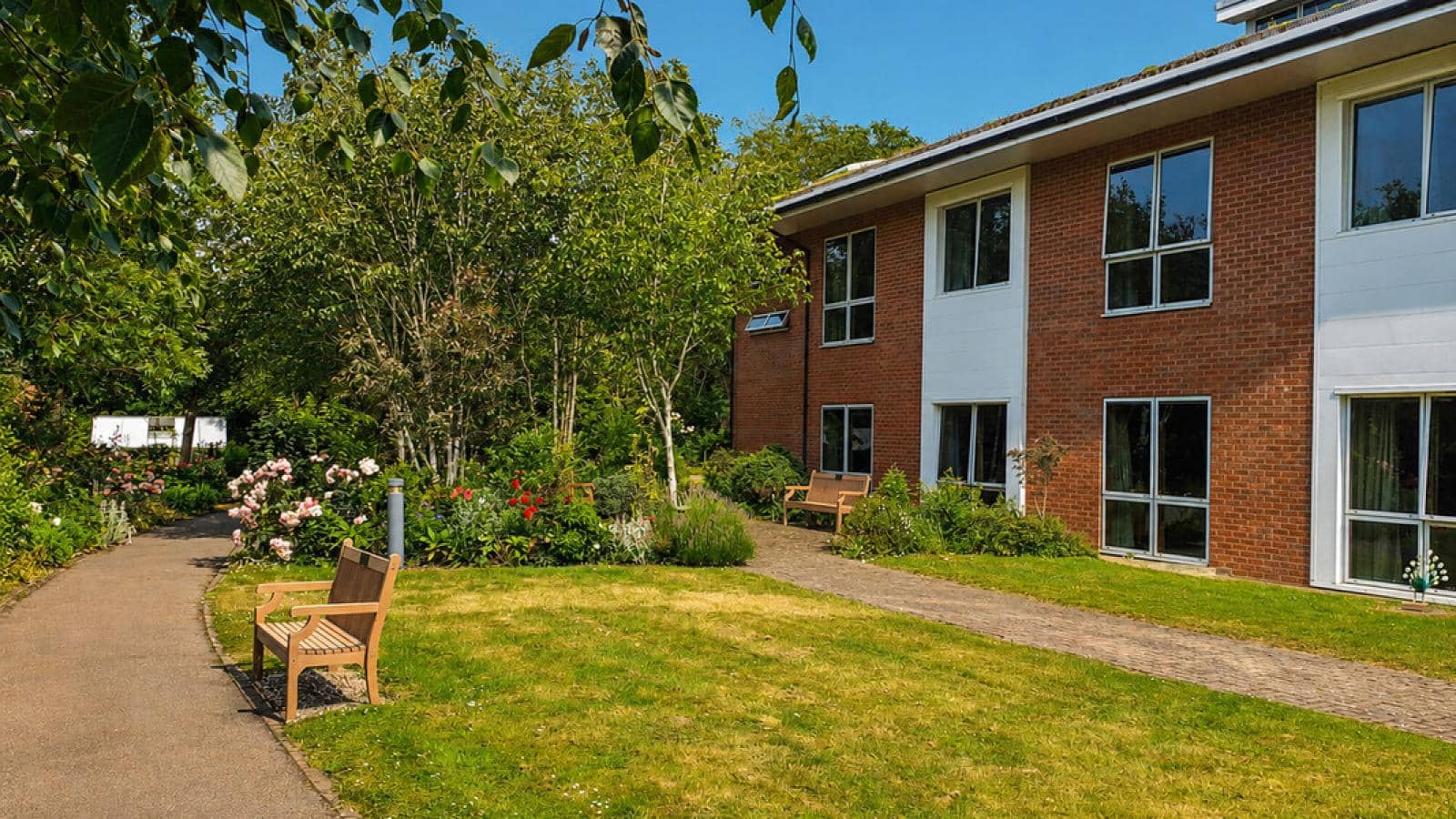 Aigburth care home in Oadby garden and pathway with bench in the sunshine