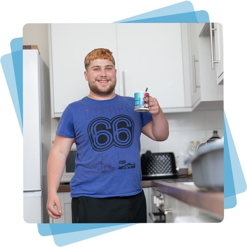 A person stood in a kitchen holding a cup of tea