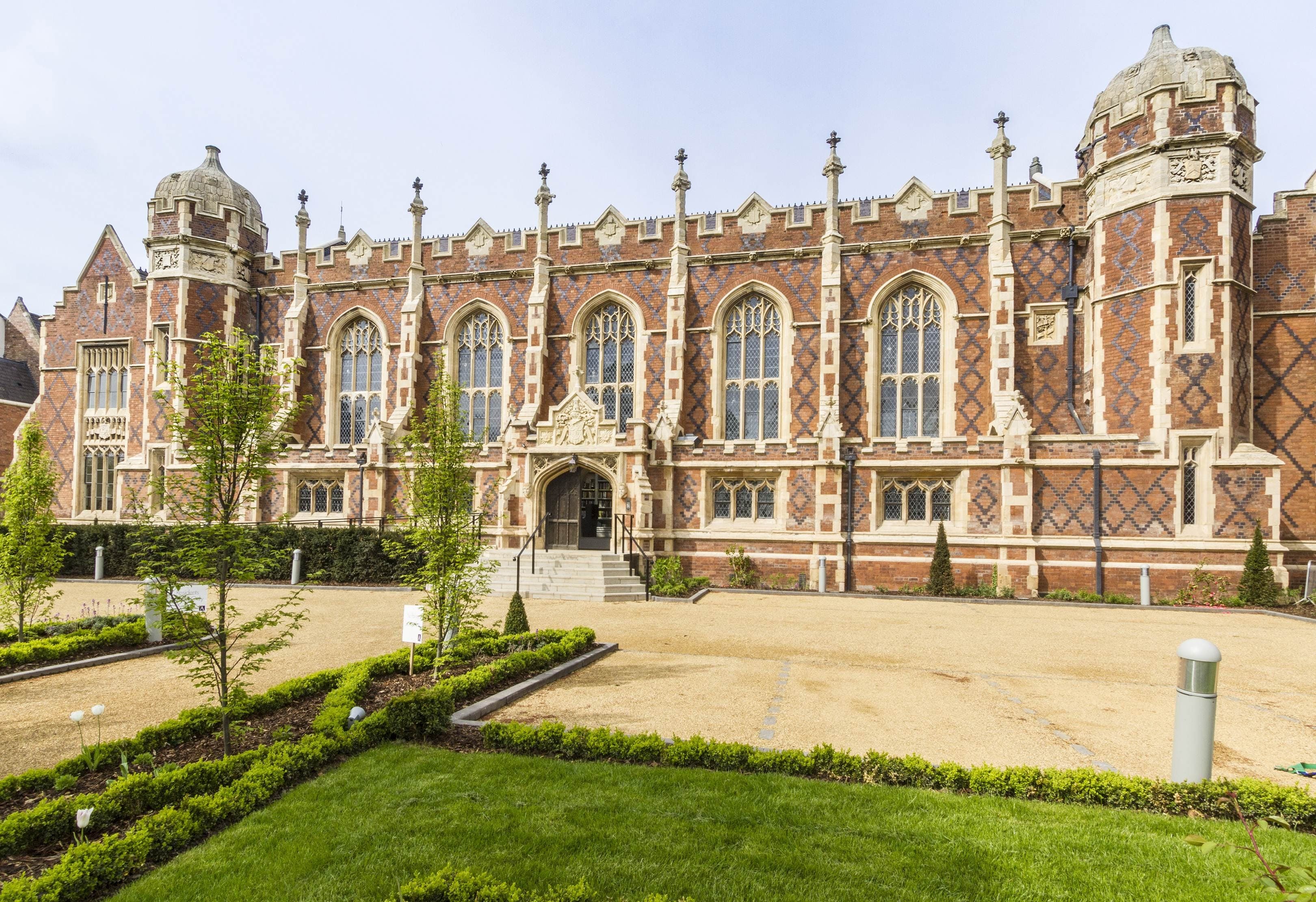 Red-brick mansion with arched windows and stone buttresses