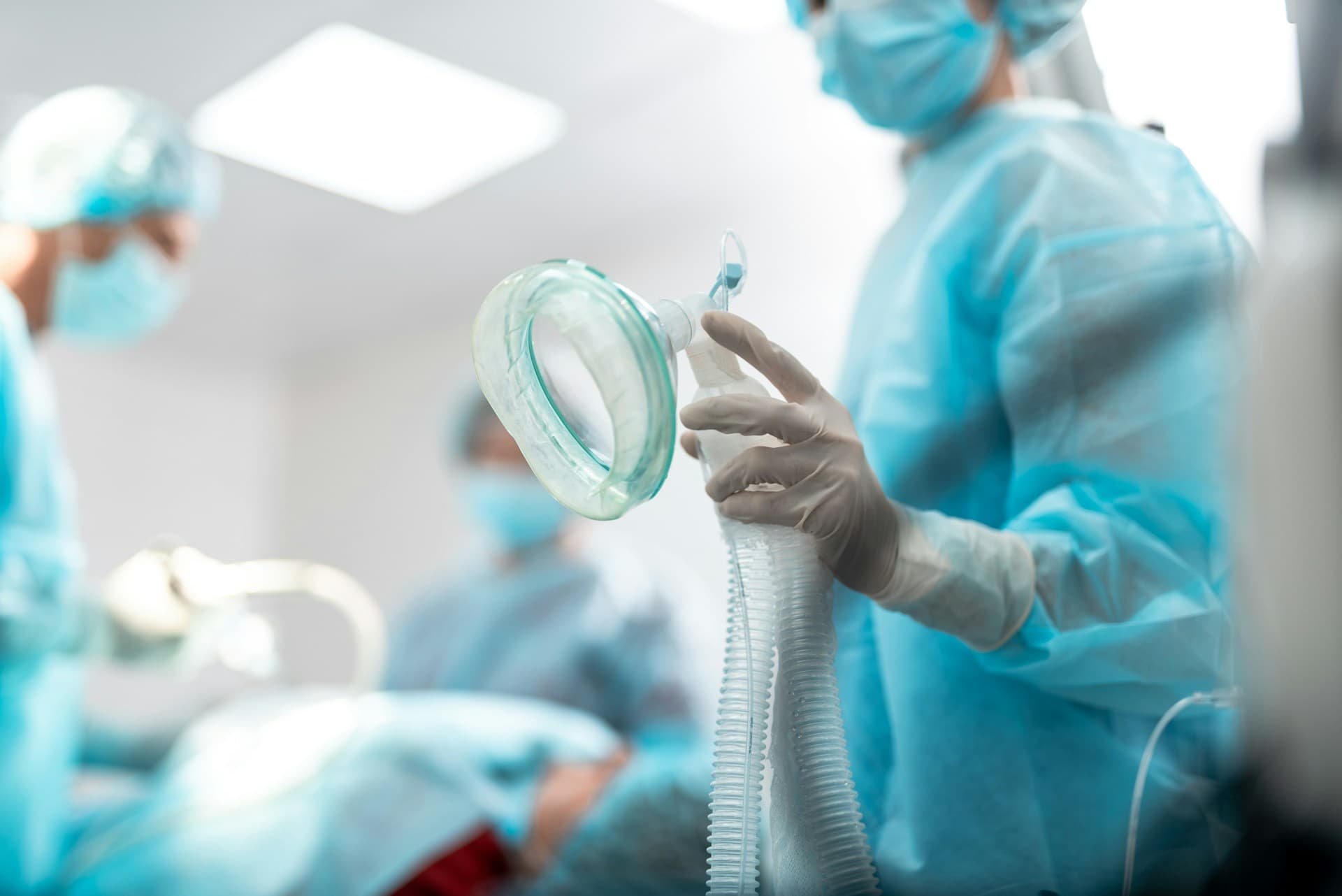 a person in surgical gown holding an oxygen mask